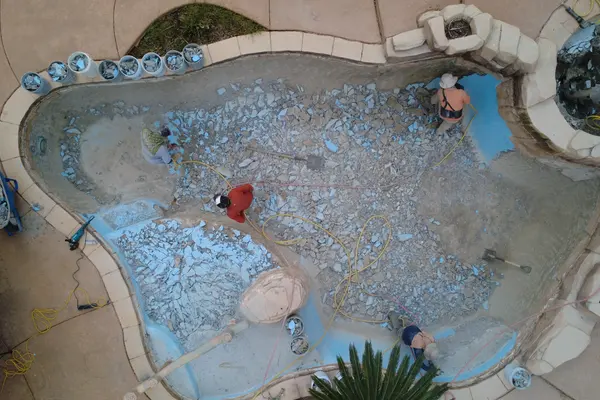 Vista aérea de la piscina con escombros de enlucido picado cubriendo todo el piso